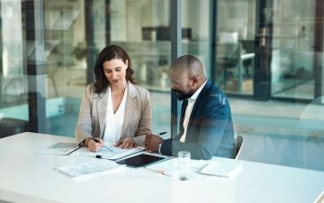 Man and woman sat at a desk in an office looking at paperwork